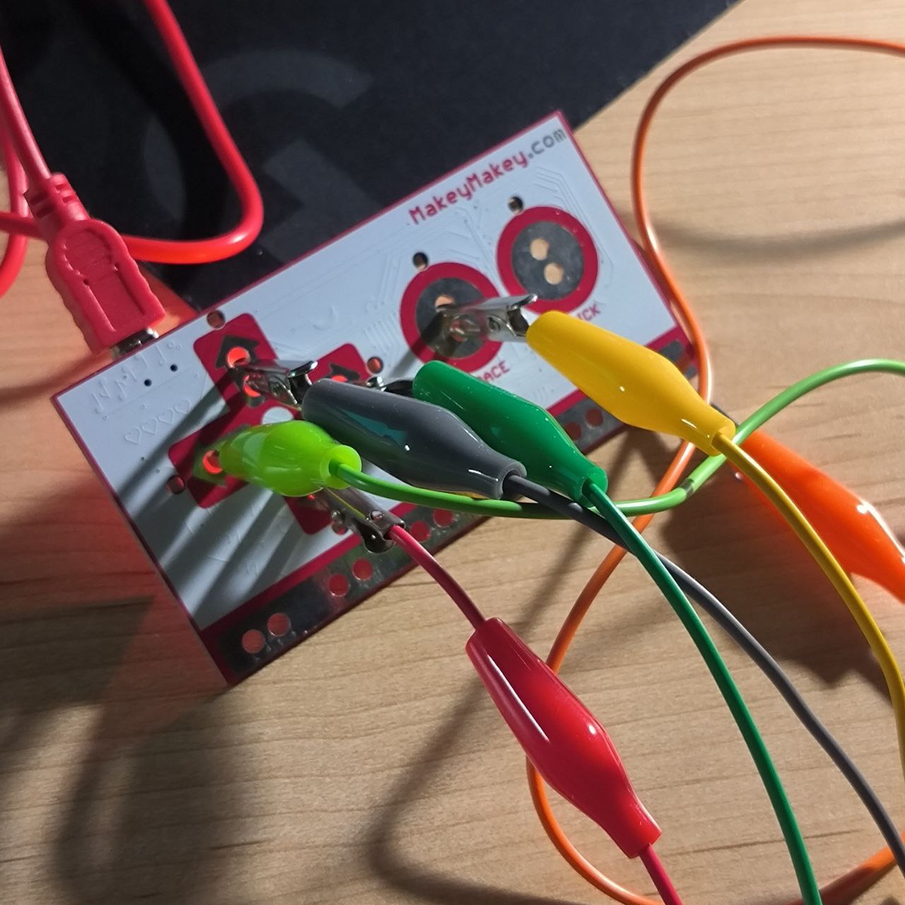 Each wire from the paper circuit is connected to the appropriate input on the Makey Makey board. The setup is now electrically complete and ready for user interaction—each touch will register as a key press.